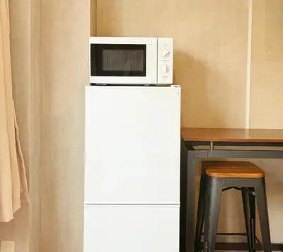 a microwave on top of a refrigerator with a table at Tokyo Hakusan Louis Apartment near TOKYO DOME close to Yamanote Line in Tokyo