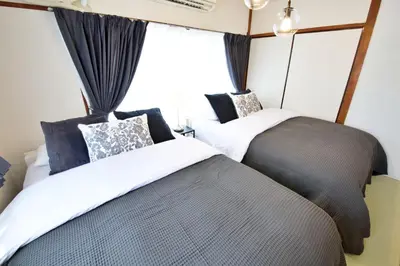 two beds in a room with a window at \u5bdb\u6c38\u5bfa\u5742\u30cf\u30a4\u30e0 803 \u6771\u4eac\u89b3\u5149\u306e\u62e0\u70b9\u306b\u6700\u9069 \u9daf\u8c37\u99c52\u5206 in Tokyo