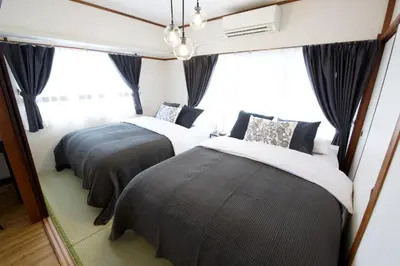 two beds in a room with windows at \u5bdb\u6c38\u5bfa\u5742\u30cf\u30a4\u30e0 803 \u6771\u4eac\u89b3\u5149\u306e\u62e0\u70b9\u306b\u6700\u9069 \u9daf\u8c37\u99c52\u5206 in Tokyo