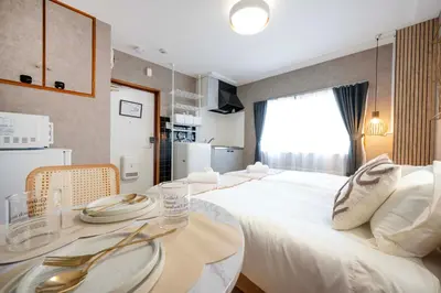 a hotel room with a large white bed and a table at All Good Stay HEIWAJIMA in Tokyo