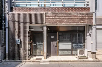 an entrance to a building with a chair on the sidewalk at t plus house ryogoku in Tokyo