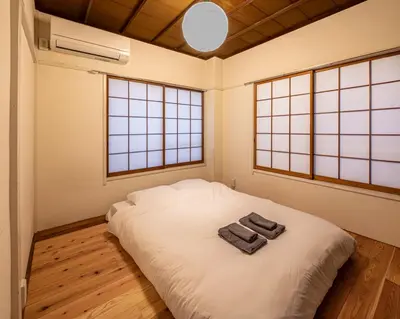 a bedroom with a white bed with two towels on it at t plus house ryogoku in Tokyo