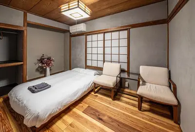 a bedroom with a bed and two chairs and a television at t plus house ryogoku in Tokyo