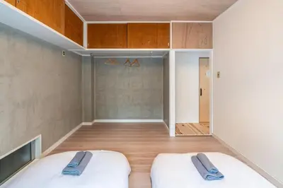 two beds in a room with wooden floors and cabinets at t plus house ryogoku in Tokyo