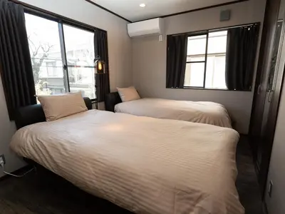 two beds in a room with two windows at Five Roses House in Tokyo