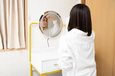 a woman looking at her reflection in a mirror at Five Roses House in Tokyo