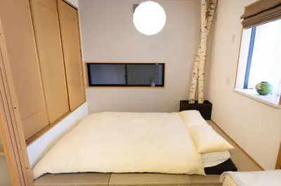 a small bedroom with a bed and a flat screen tv at Five Roses House in Tokyo