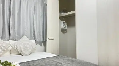 a bedroom with a bed with white sheets and a window at Ikebukuro Area 1F3 KamiikeApartment in Tokyo