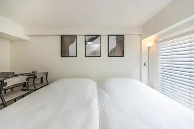 a white bedroom with a bed and a table at 20 minutes by Haneda Airport train 3-minute walk from Kamata Station Direct access to Tokyo, Yokohama, Ueno in Tokyo