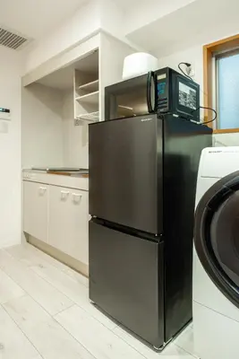 a kitchen with a black refrigerator and a microwave at 20 minutes by Haneda Airport train 3-minute walk from Kamata Station Direct access to Tokyo, Yokohama, Ueno in Tokyo