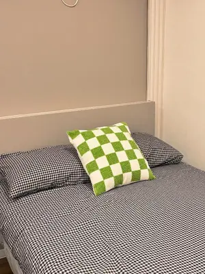 a bed with a green and white checkered pillow on it at TOMI Hotel in Tokyo