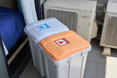 two trash cans with stickers on them next to air conditioners at Shamrock Aoto 303 Cozy Tokyo Stay Near Station Airport Disney Access in Tokyo