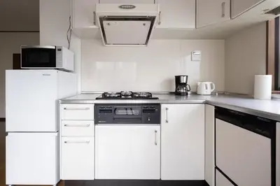 a white kitchen with a stove and a microwave at \u5713\u798f\u30d3\u30eb in Tokyo