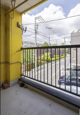 a balcony with a yellow wall and metal railing at \u5713\u798f\u30d3\u30eb in Tokyo
