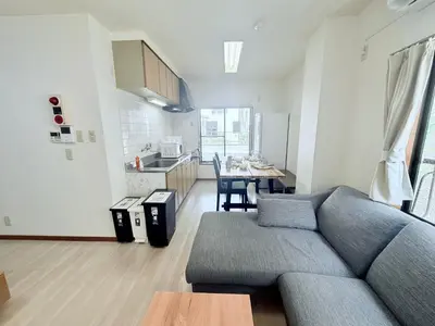a living room with a gray couch and a kitchen at Terrace Stay Omori in Tokyo