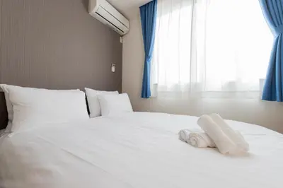 a white bed with towels on it in front of a window at Vista Stay Oshiage in Tokyo