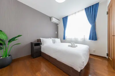 a bedroom with a large bed with blue curtains at Vista Stay Oshiage in Tokyo