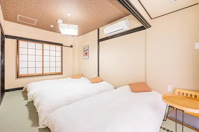 two beds in a room with a table and a window at \u6de1\u8def\u753a\u99c5\u304b\u3089\u5f92\u6b691\u5206 140\u5e73 4ldk \u65b0\u5bbf\u99c512\u5206 \u79cb\u8449\u539f5\u5206 \u6771\u4eac\u99c57\u5206 \u9280\u5ea7\u99c57\u5206 \u6e0b\u8c3720\u5206 in Tokyo