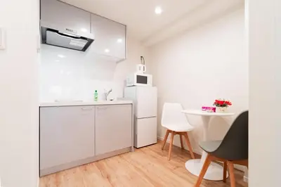 a white kitchen with a table and a white refrigerator at Waseda Star New Open Station 2 Minutes in Tokyo