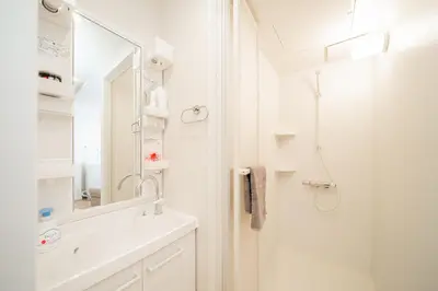a white bathroom with a shower and a sink at Waseda Star New Open Station 2 Minutes in Tokyo