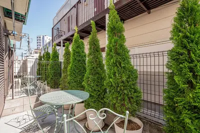 a table and chairs on a balcony with trees at Shinjuku Terrace 226 BnB in Tokyo