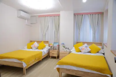 a bedroom with two beds with yellow sheets and windows at \u6771\u4eac\u685c\u306e\u5bbf in Tokyo