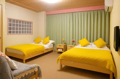 a room with two beds with yellow sheets at \u6771\u4eac\u685c\u306e\u5bbf in Tokyo