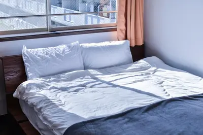 an unmade bed in a room with a window at Aoi Bld 3F in Tokyo