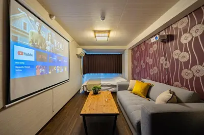 a small living room with a couch and a large screen at \u9580\u524d\u4ef2\u753a\u306e\u685c\u3092\u81e8\u3080\u6c11\u6cca LINKAGE STAY Monzen Nakacho in Tokyo
