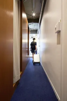 a man walking down a hallway with a suitcase at MIDORIso Nihonbashi in Tokyo