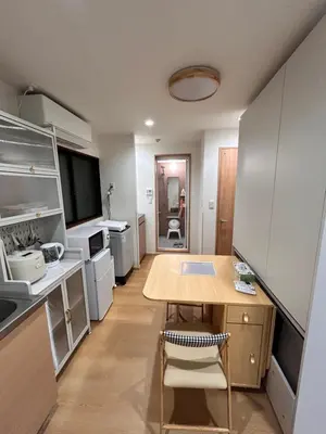 a small kitchen with a wooden table and a dining room at Askusa\u4f4f\u5409\u9928 \u6d45\u8349\u8fd1\u304f\u7573\u306e\u548c\u5ba4\u5bb6\u65cf\u3084\u30b0\u30eb\u30fc\u30d7\u306b\u3074\u3063\u305f\u308a\u306e\u90e8\u5c4b\u4e0a\u91ce\u79cb\u8449\u539f\u9280\u5ea7\u516d\u672c\u6728\u99c5\u76f4\u901a in Tokyo