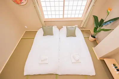two beds in a room with a window at Askusa\u4f4f\u5409\u9928 \u6d45\u8349\u8fd1\u304f\u7573\u306e\u548c\u5ba4\u5bb6\u65cf\u3084\u30b0\u30eb\u30fc\u30d7\u306b\u3074\u3063\u305f\u308a\u306e\u90e8\u5c4b\u4e0a\u91ce\u79cb\u8449\u539f\u9280\u5ea7\u516d\u672c\u6728\u99c5\u76f4\u901a in Tokyo