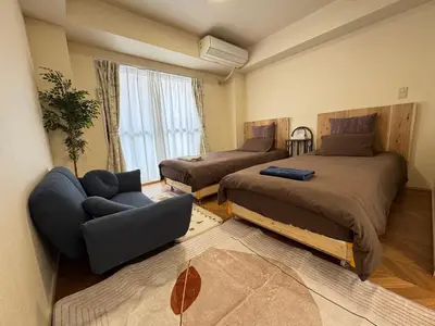 a bedroom with two beds and a couch at \u4e1c\u4eac#2\u6574\u5957\u623f\u6e90\u8fd1\u6c60\u888b\u65b0\u5bbf\u72ec\u7acb\u6d17\u624b\u95f4\u53a8\u623f\u53cc\u5e8a\u53ef\u4f4f2\u52303\u4eba in Tokyo