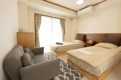a hotel room with two beds and a couch at \u4e1c\u4eac#3\u6574\u5957\u623f\u6e90\u8fd1\u6c60\u888b\u65b0\u5bbf\u72ec\u7acb\u6d17\u624b\u95f4\u53a8\u623f\u53cc\u5e8a\u53ef\u4f4f2\u52303\u4eba in Tokyo