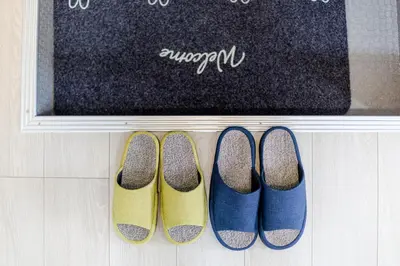 a row of four pairs of shoes in front of a chalkboard at Iriya House\u5165\u8c37\u516c\u5bd3702 in Tokyo