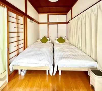 two beds in a room with wooden floors and windows at Direct to Akihabara Shinjuku Max 6 people in Tokyo