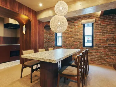 a dining room with a table and chairs and a brick wall at illi Rug Hamamatsucho in Tokyo