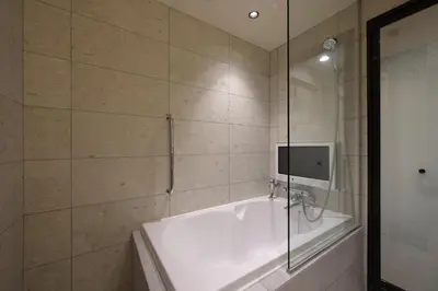a bathroom with a tub and a glass shower at HOTEL MINATO Azabu-juban in Tokyo