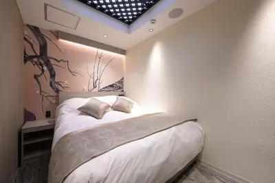 a bedroom with a bed with a tree mural on the wall at HOTEL MINATO Azabu-juban in Tokyo