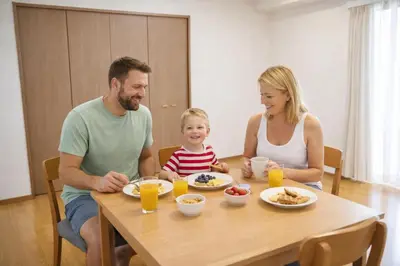 a family sitting at a table eating food at 7th floor 702 with elevator, Minato area, 40 square meters, near Tokyo Tower, direct train to Haneda Airport, Narita Airport in Tokyo