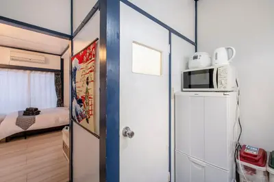 a small room with a microwave on top of a refrigerator at Central Panda Hotel in Tokyo