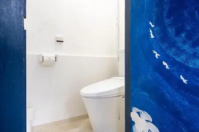 a bathroom with a toilet with a blue shower curtain at Central Panda Hotel in Tokyo