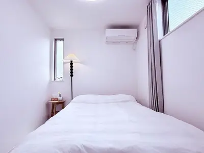 a white bedroom with a bed and a window at Yodamari House Ikebukuro Direct access to Shinjuku and Shibuya7 people OK! in Tokyo