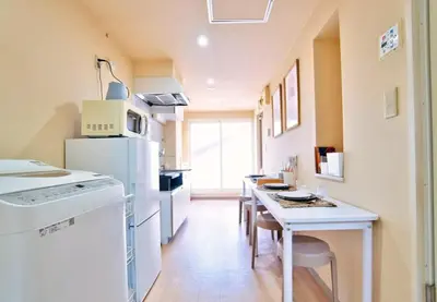 a kitchen with white appliances and a table with chairs at I HOUSE jujo in Tokyo