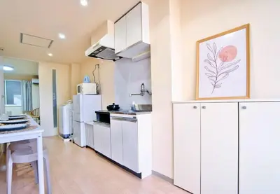 a kitchen with white cabinets and a white refrigerator at I HOUSE jujo in Tokyo