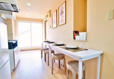a kitchen with a white island with stools at I HOUSE jujo in Tokyo