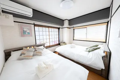 two beds in a room with two windows at 50 \u5e73\u65b9 - \u65b0\u5bbf 1 \u7ad9\u5730 - \u65b0\u5927\u4e45\u4fdd\u7ad9 4 Min - \u6b4c\u821e\u4f0e\u753a 4 Min - Sakura 404 in Tokyo