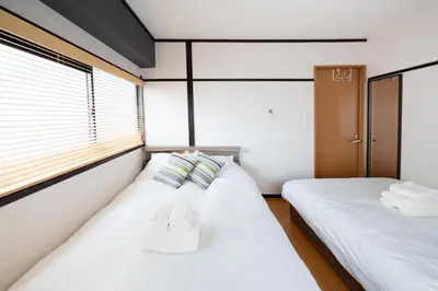 two beds in a small room with white sheets at 50 \u5e73\u65b9 - \u65b0\u5bbf 1 \u7ad9\u5730 - \u65b0\u5927\u4e45\u4fdd\u7ad9 4 Min - \u6b4c\u821e\u4f0e\u753a 4 Min - Sakura 404 in Tokyo
