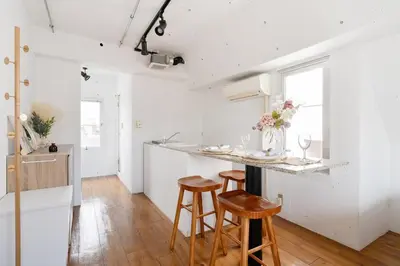 a kitchen with white walls and wooden stools at Casa di Luce - Stylish Stay near Shibuya & Meguro River Room405 in Tokyo
