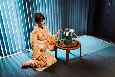 a woman in a kimono sitting next to a table at Villa Boushu KURAMAE in Tokyo